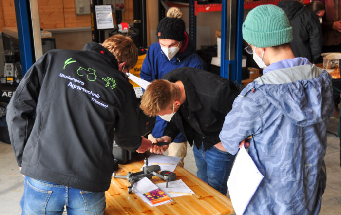 Betrachtung einer auseinander gebauten Drohne durch Studenten