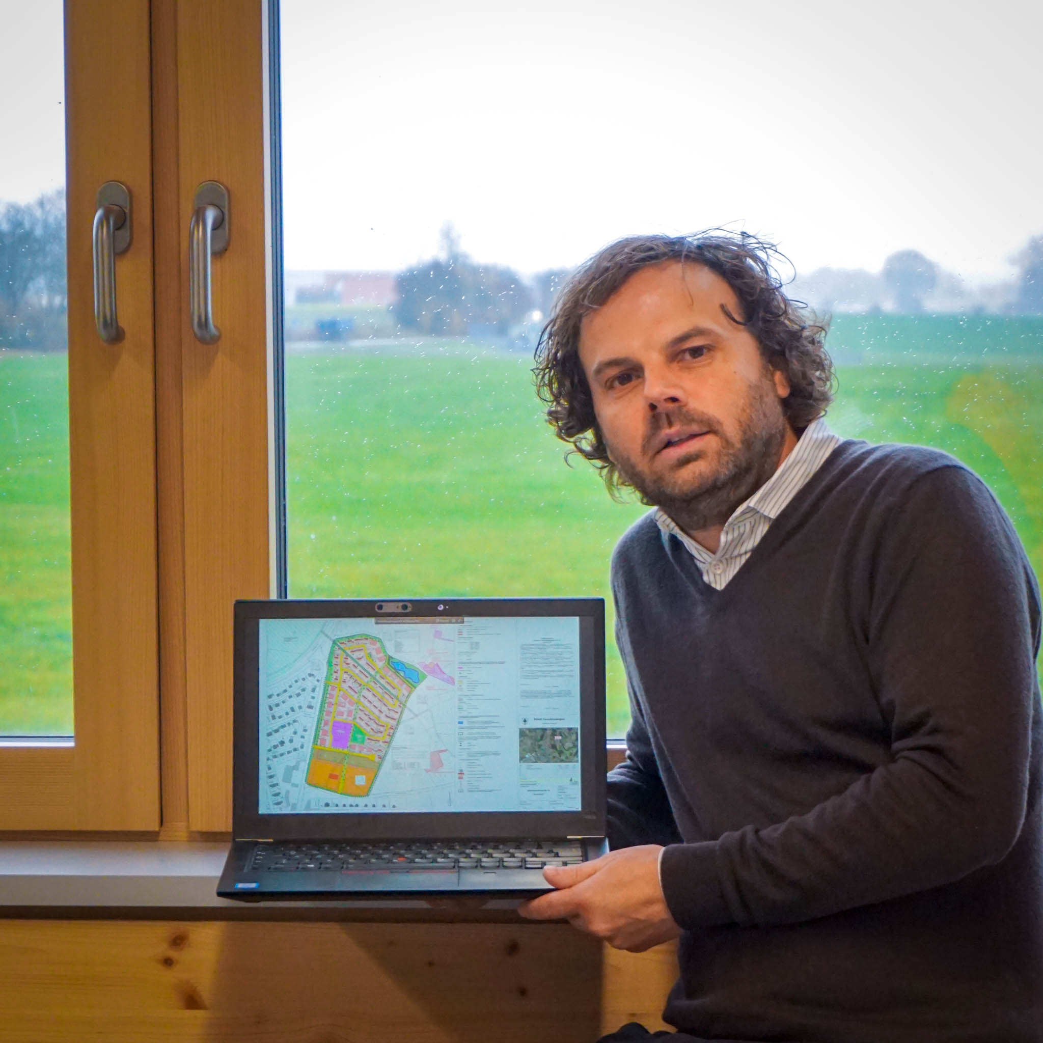 Prof. Jungwirth vor dem Fenster zum Baugebiet Hochschule