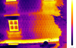 Titelbild des Blogbeitrages. Zusehen ist ein Haus, aufgenommen mit einer Infrarotkamera. Erklärung: Helle Stellen in der Thermographie-Aufnahme deuten auf unzureichende Isolierung an Sockel, Heizkörpernische, Fenster und Rollo Kasten hin.